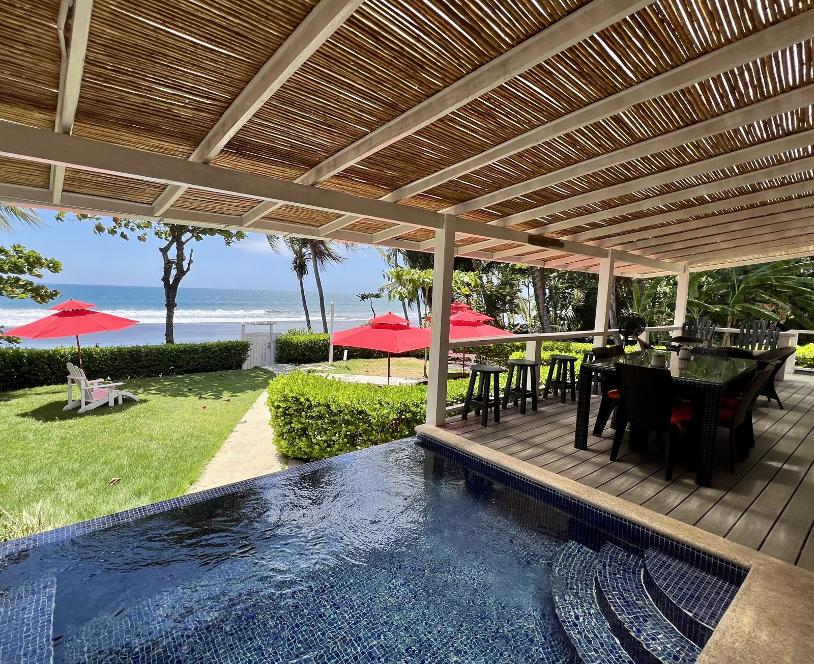 Infinity plunge pool and bamboo-roofed porch at The Palm, Beach House, looking across the garden to the beach and the Pacific