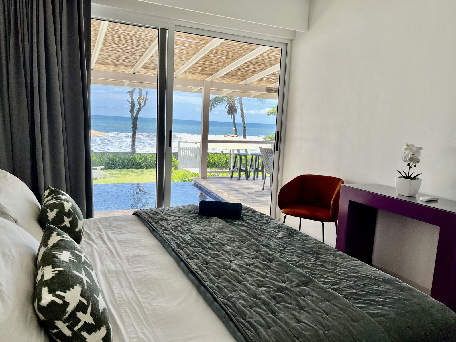 Bedroom with a king bed and sliding glass doors opening toward the pool and the ocean