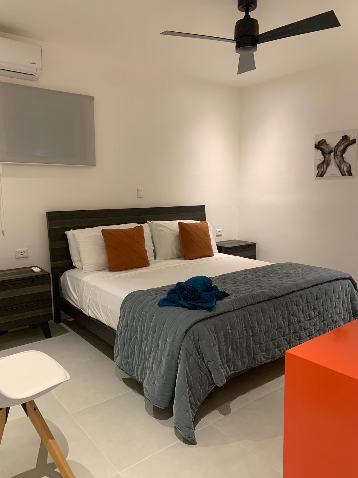 Bedroom with a queen bed, gray quilt and orange pillows