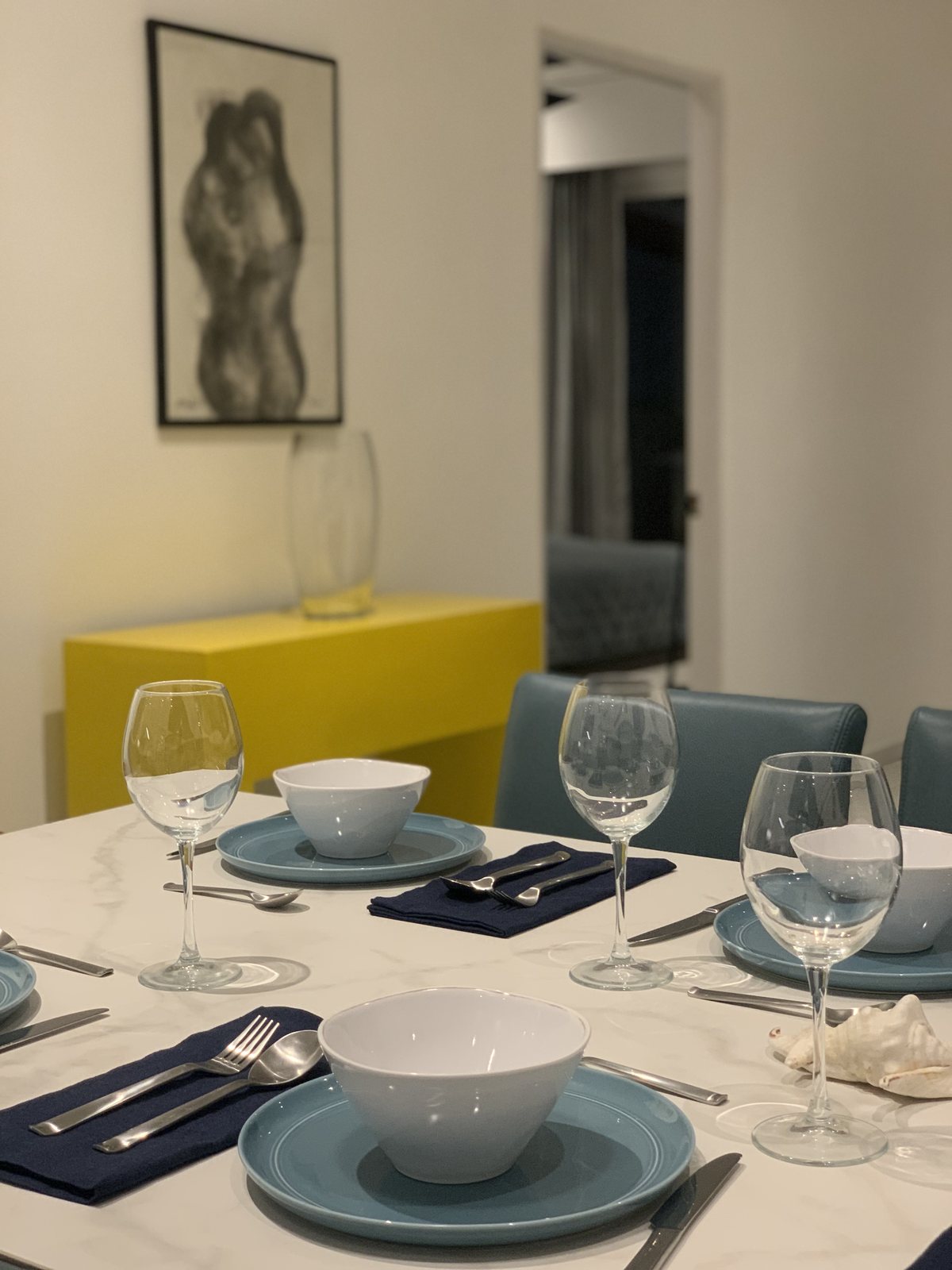 Close-up of a place setting on the dining table with a yellow console behind